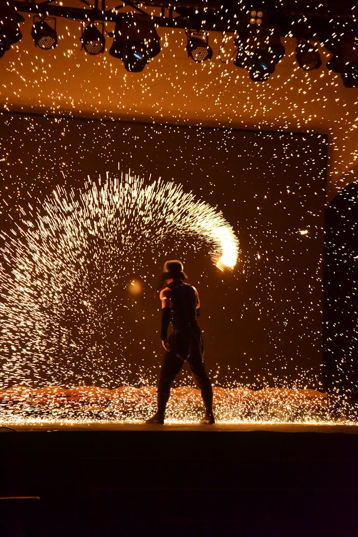 About Exciting fire performance with vibrant sparks against a dark background.