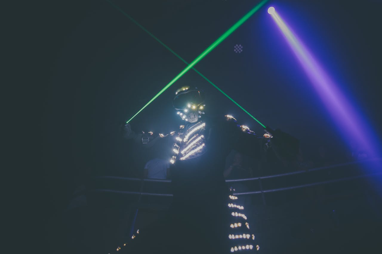 About Futuristic dancer in illuminated suit performing under vibrant neon lights.